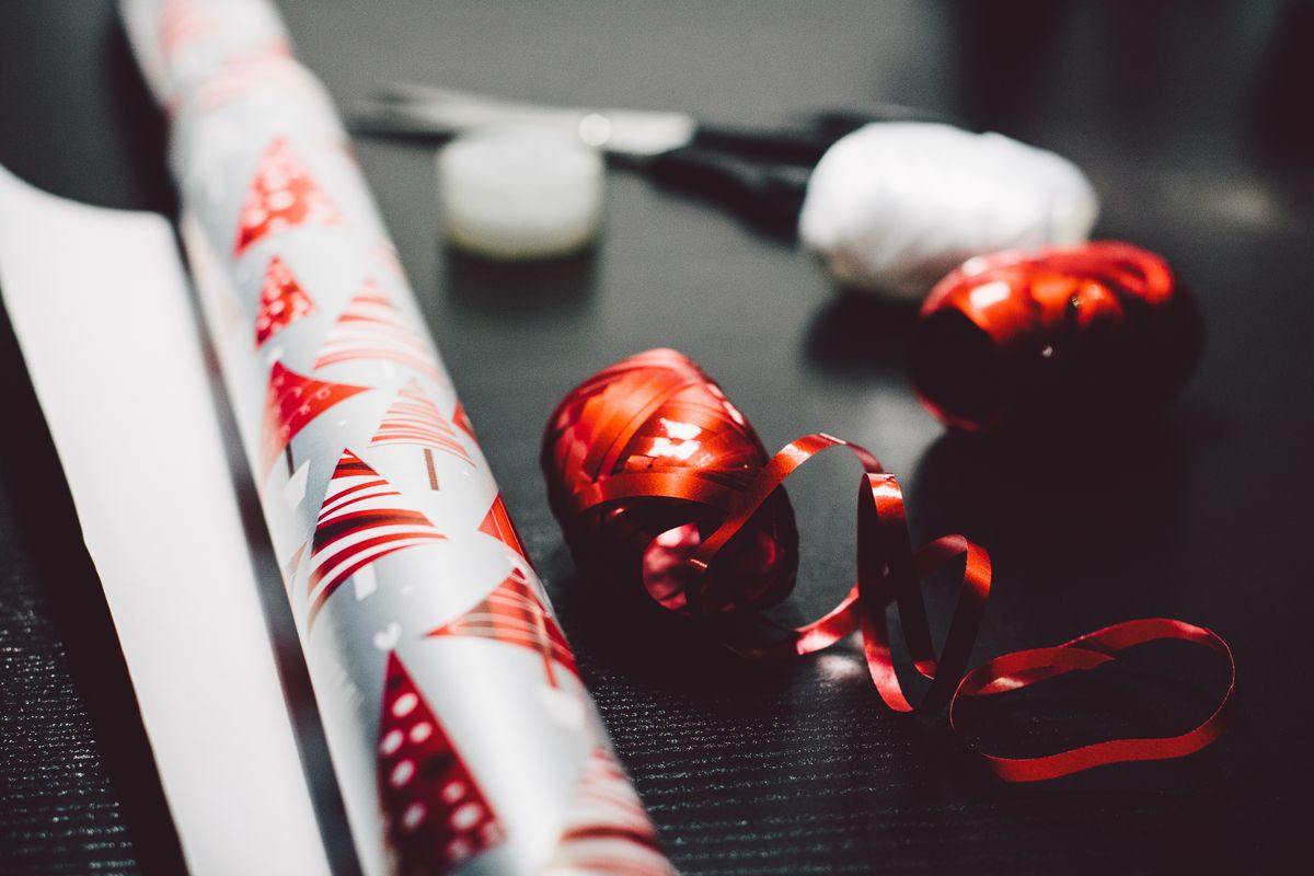 Colorful gift wrapping paper and red ribbon set the tone for holiday gift preparation.