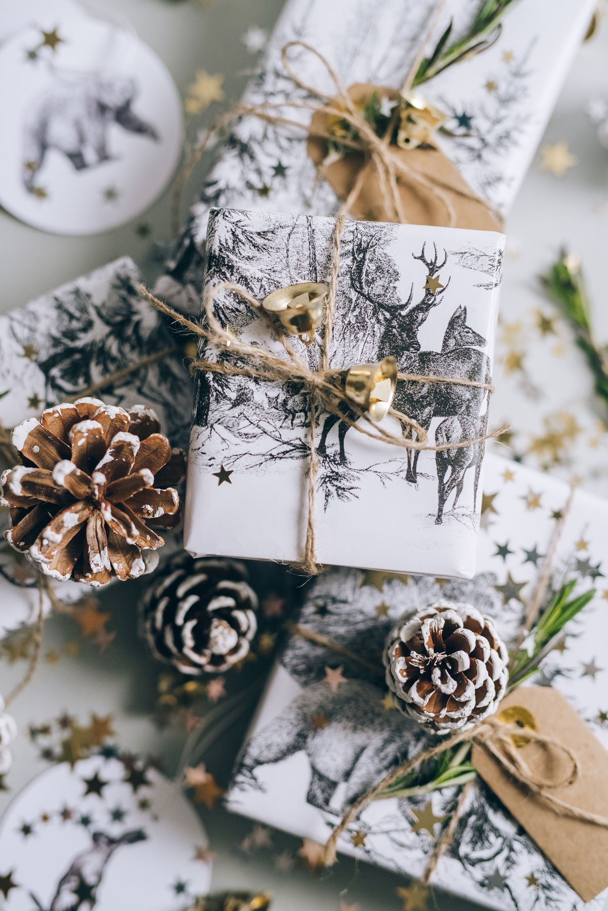 Beautifully wrapped Christmas gifts with pine cones and gold stars in a festive setting.