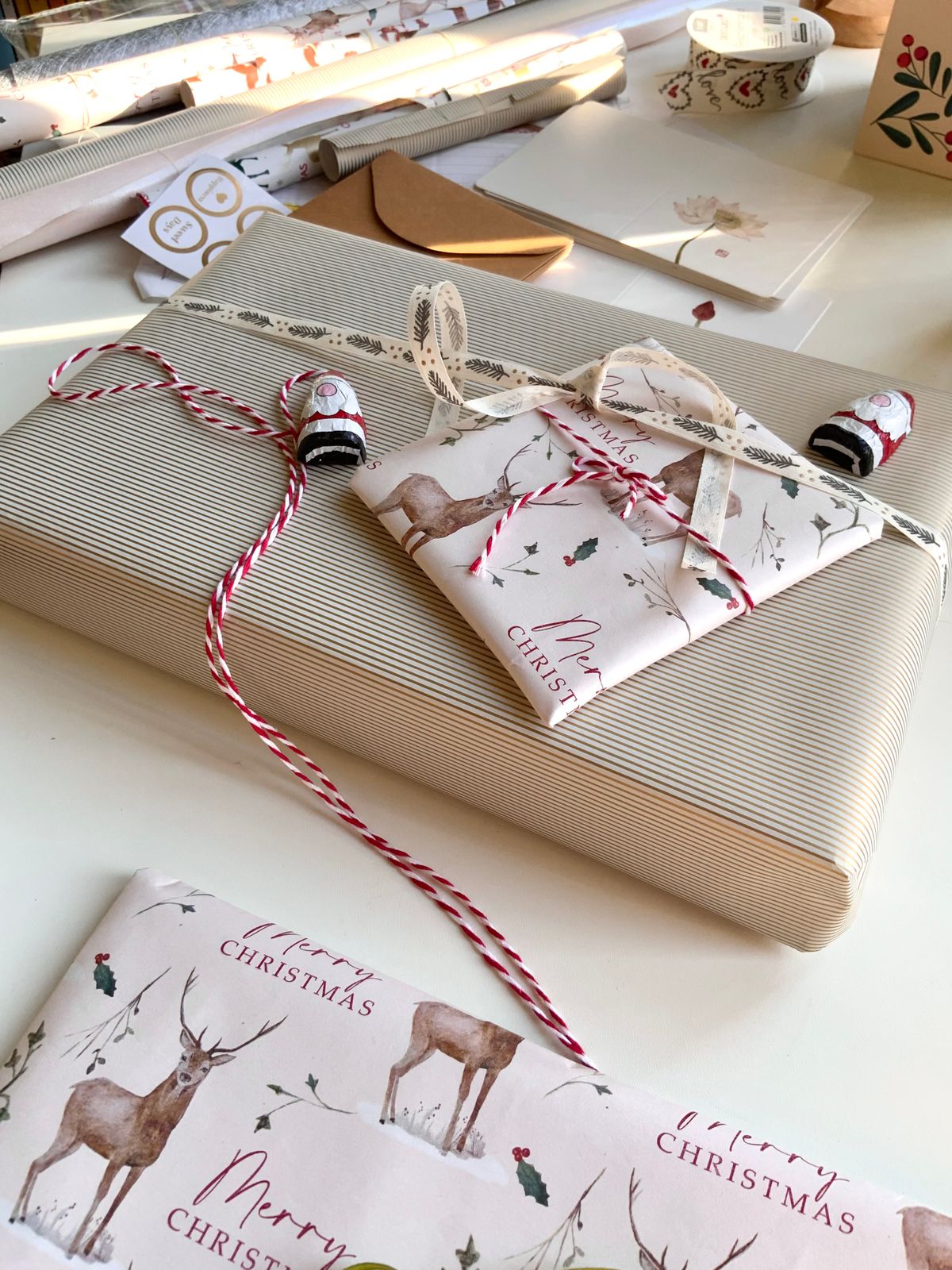 Beautifully wrapped Christmas presents with deer-themed paper and red twine.